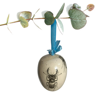 Jajko wielkanocne z błękitną wstążeczką. Muchy, żuki i wije