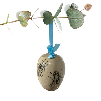 Jajko wielkanocne z błękitną wstążeczką. Mucha i żuczki